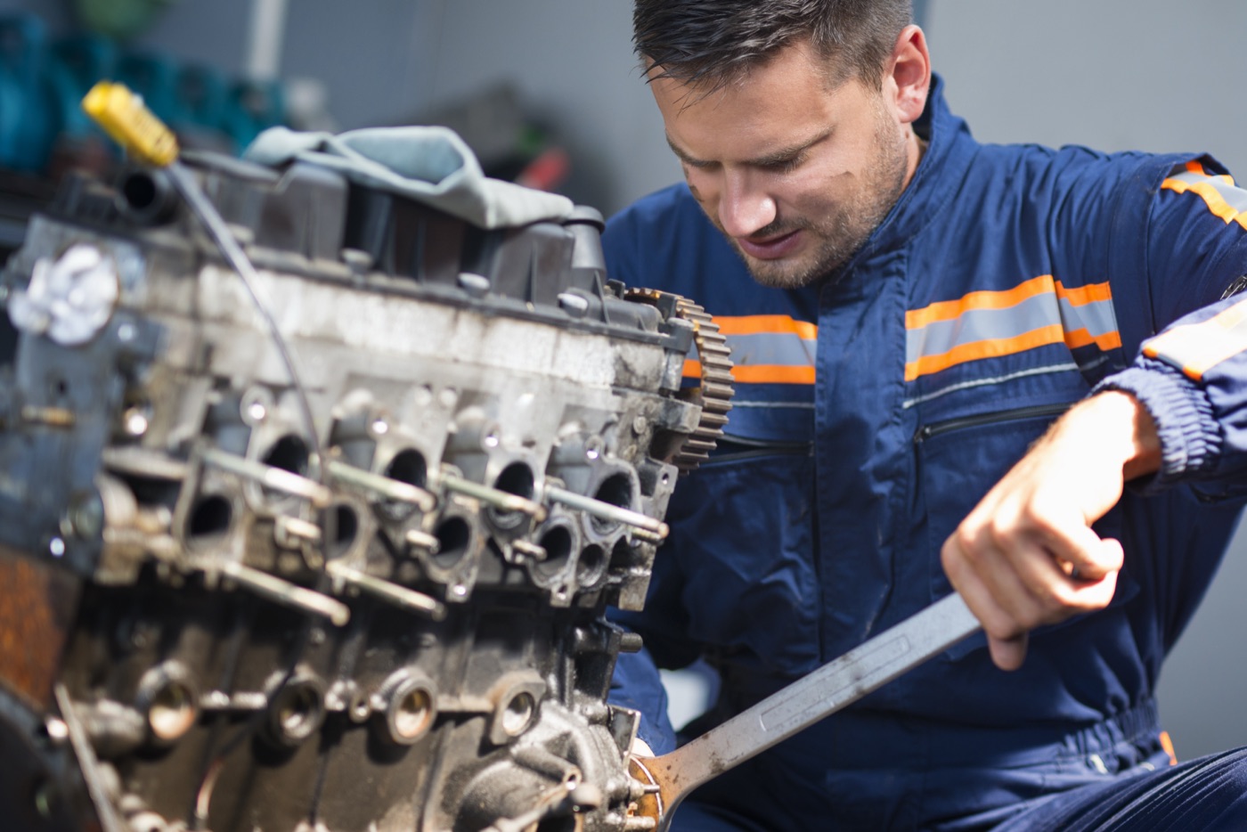 A mechanic using a wrench to work on a vehicle engine