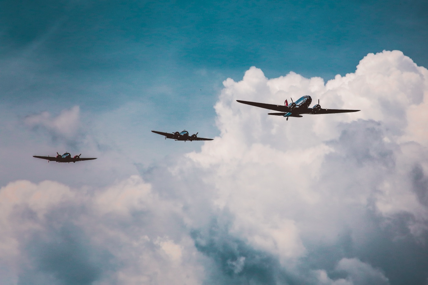 Vintage aircraft flying in formation beneath clouds