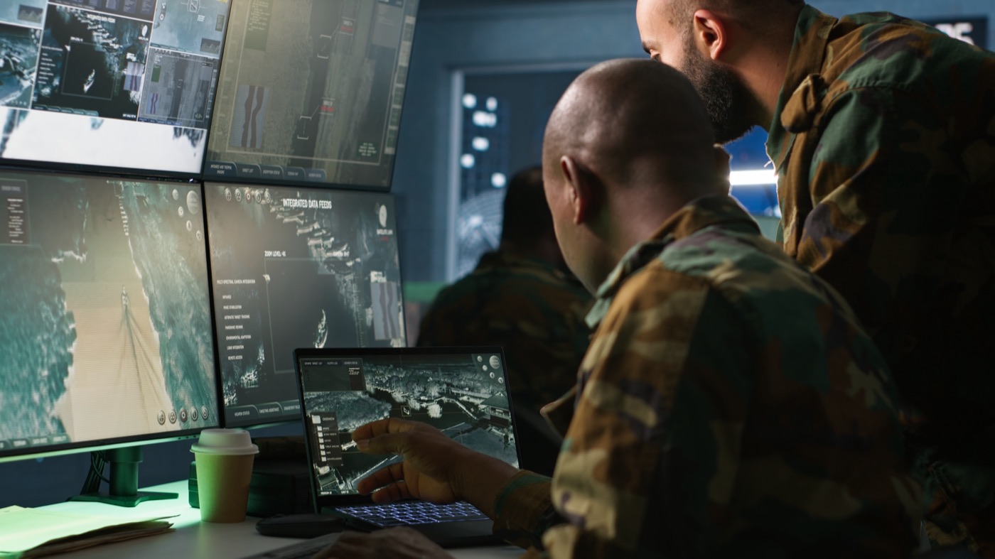 A team in military uniforms reviewing computer monitors