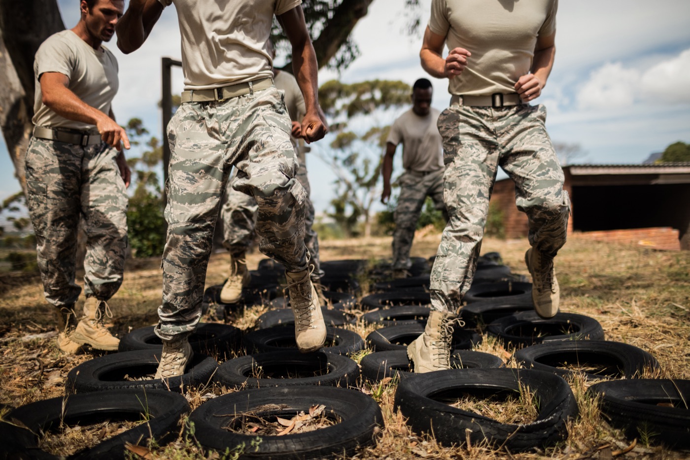 People in camouflage trousers completing a tire obstacle course