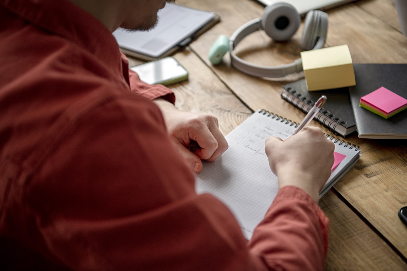 A student writing in a notebook during a study session