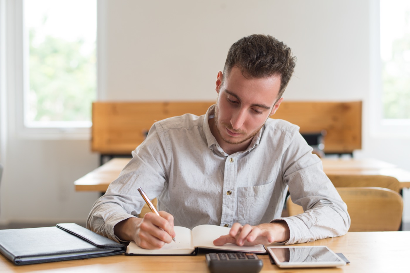 A student working through notes at a classroom desk