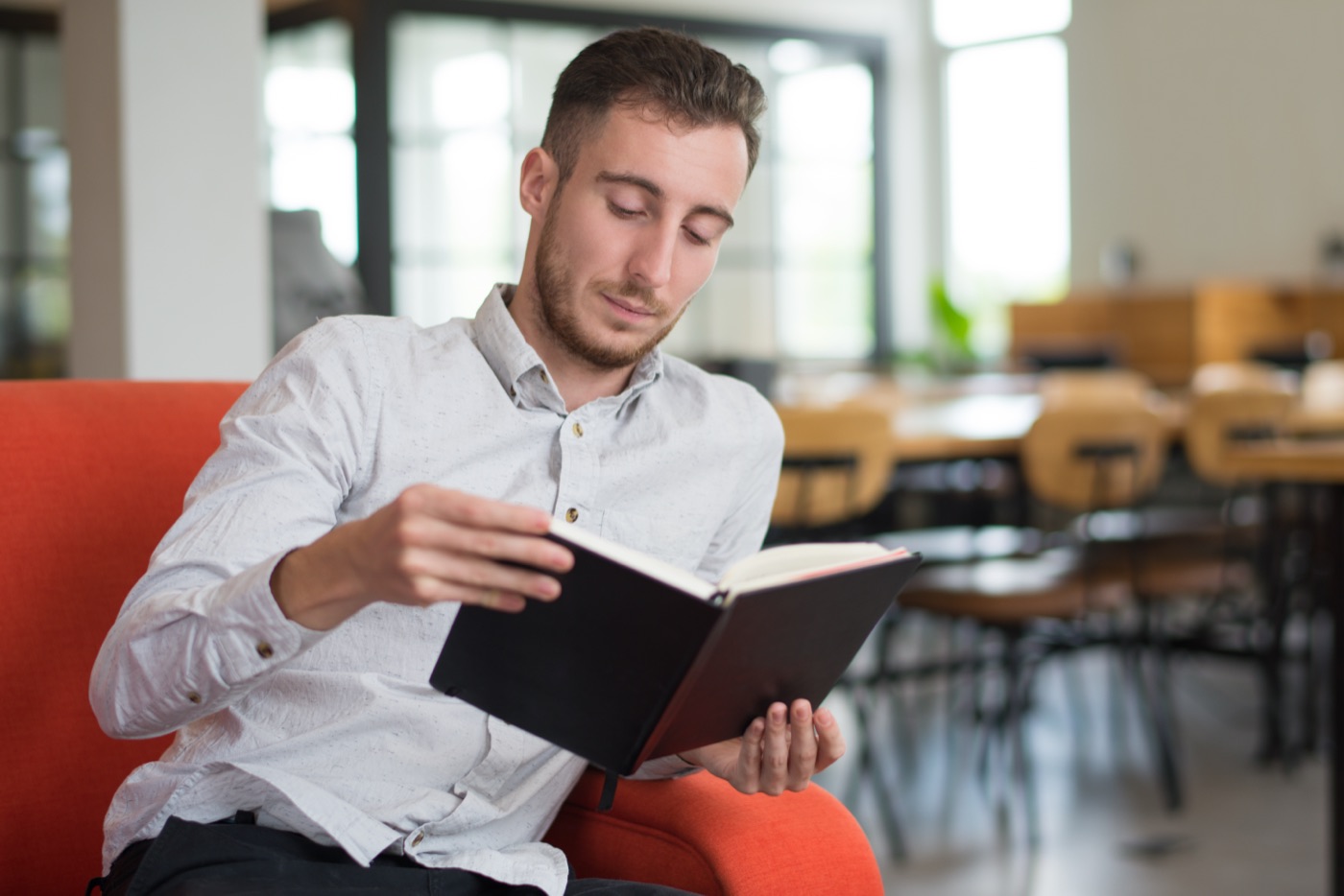 A male student reading a book in a seating area