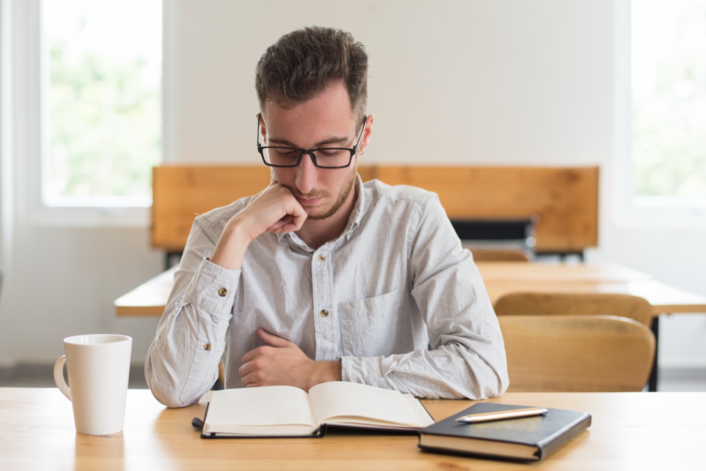 A student reading a book at a classroom desk