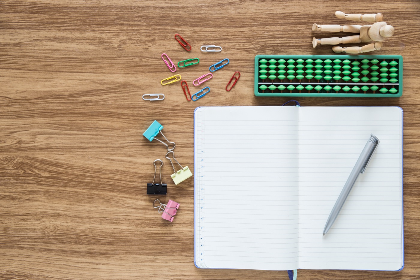 A notebook and geometric shapes arranged on a wooden desk