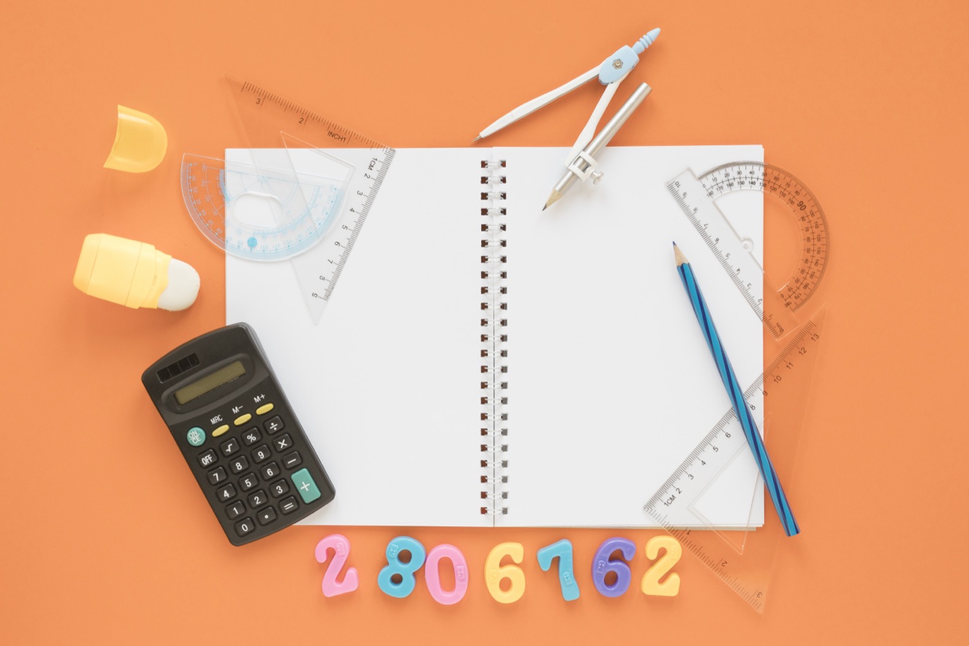 A calculator, notebook, and geometry tools arranged for practice