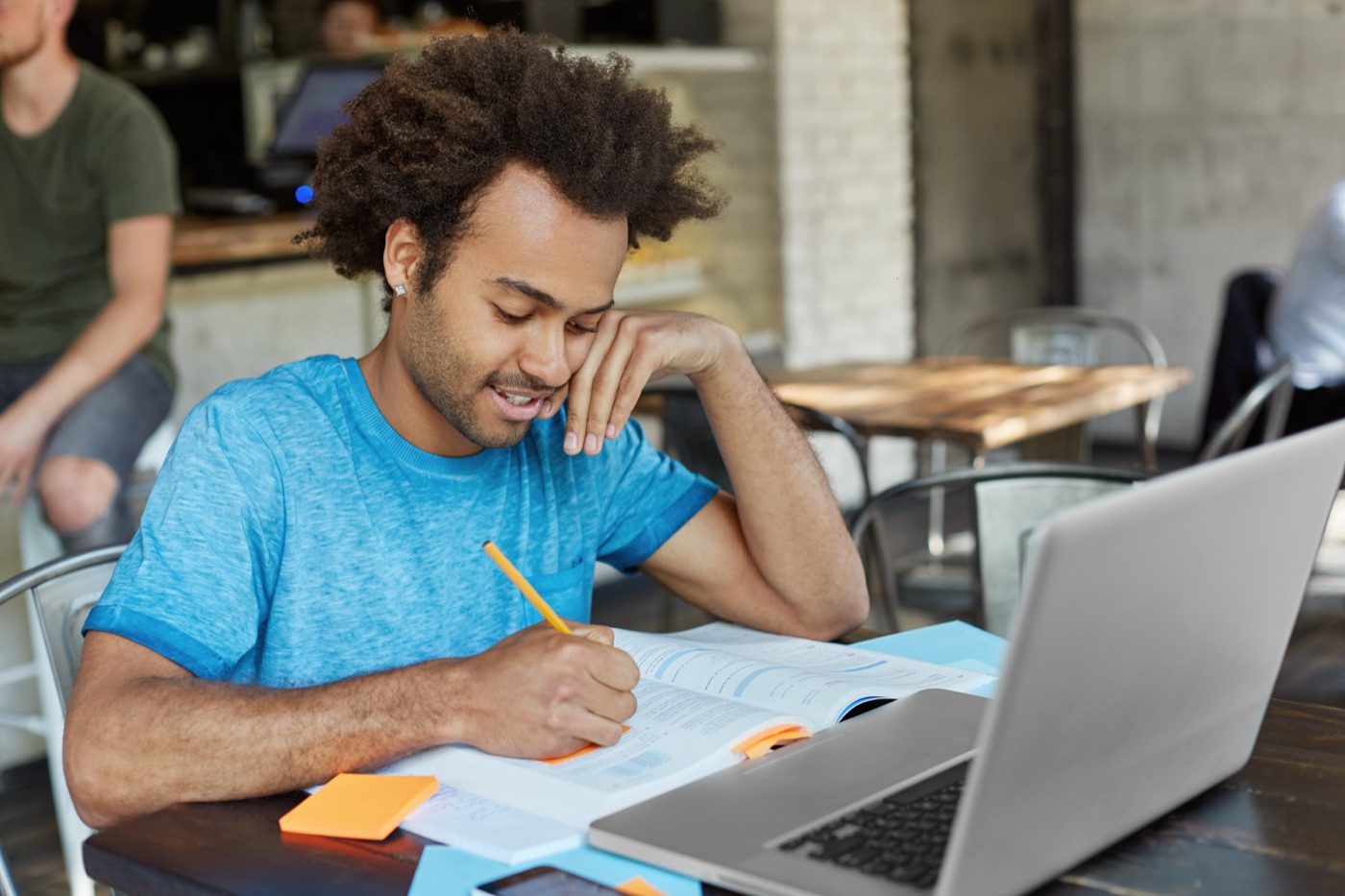 A student taking notes beside a laptop